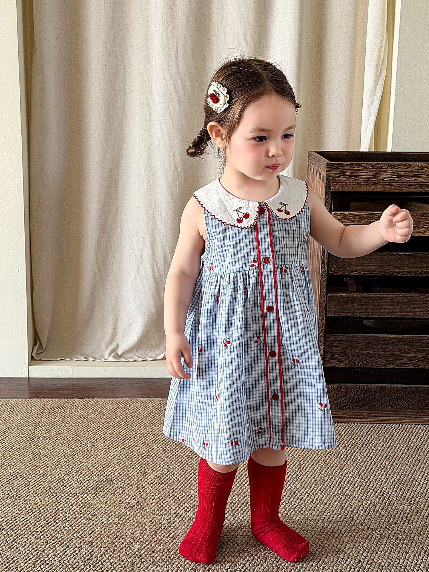 A young girl in a blue-striped cotton pinafore with a white embroidered collar.