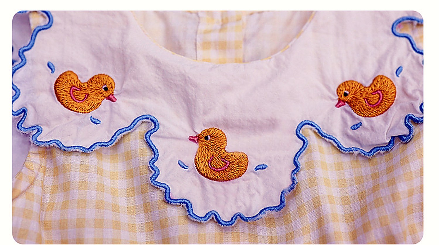 Close detail of the embroidered collar of the Buttercup Pinafore — daisies and ducklings.