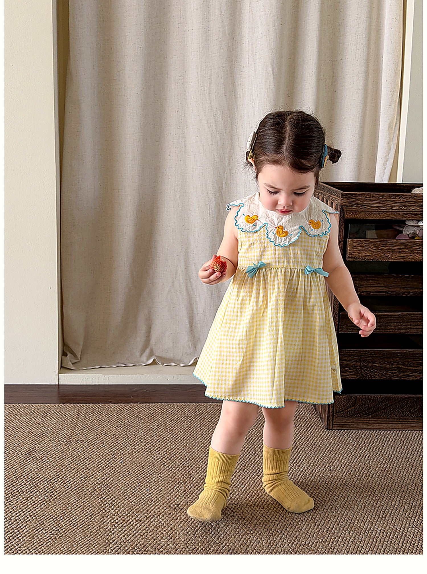 A girl in the Buttercup Pinafore, a vintage butter-yellow gingham pinafore.