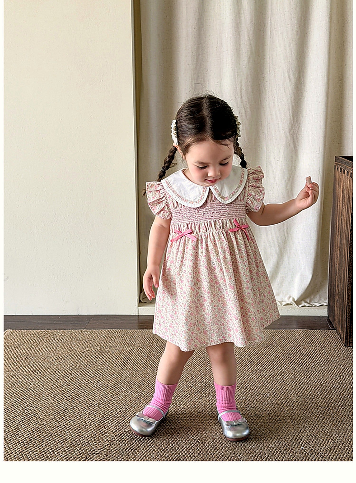 A young girl in the warm-pink Campion Dress on a warm summer day.