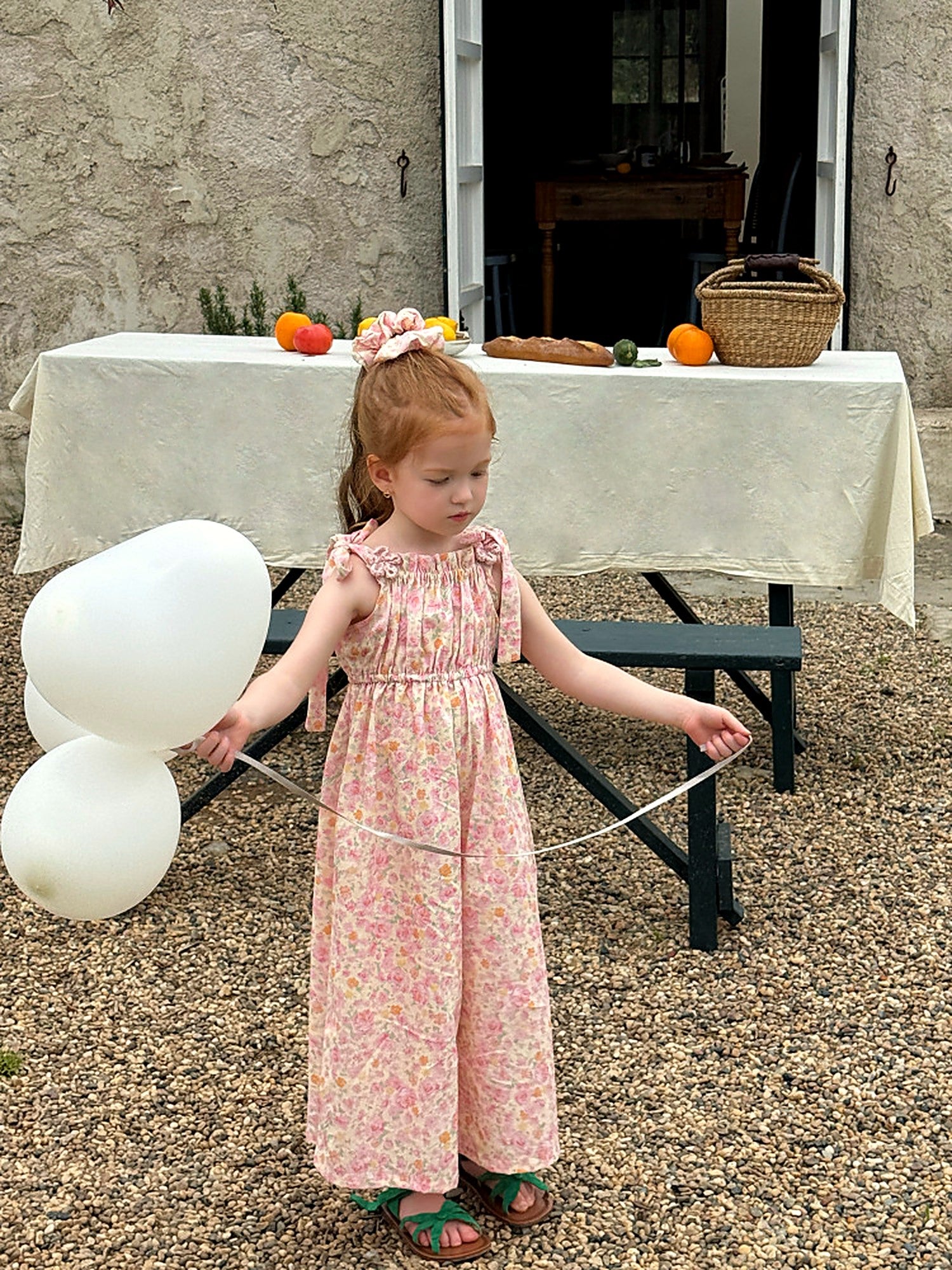A girl in the Clover Romper, a vintage wide-leg jumpsuit in pink floral.
