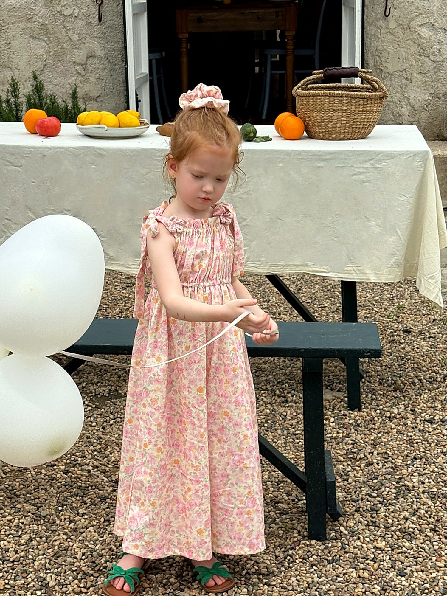 A girl in the Clover Romper by a courtyard table, soft afternoon light.