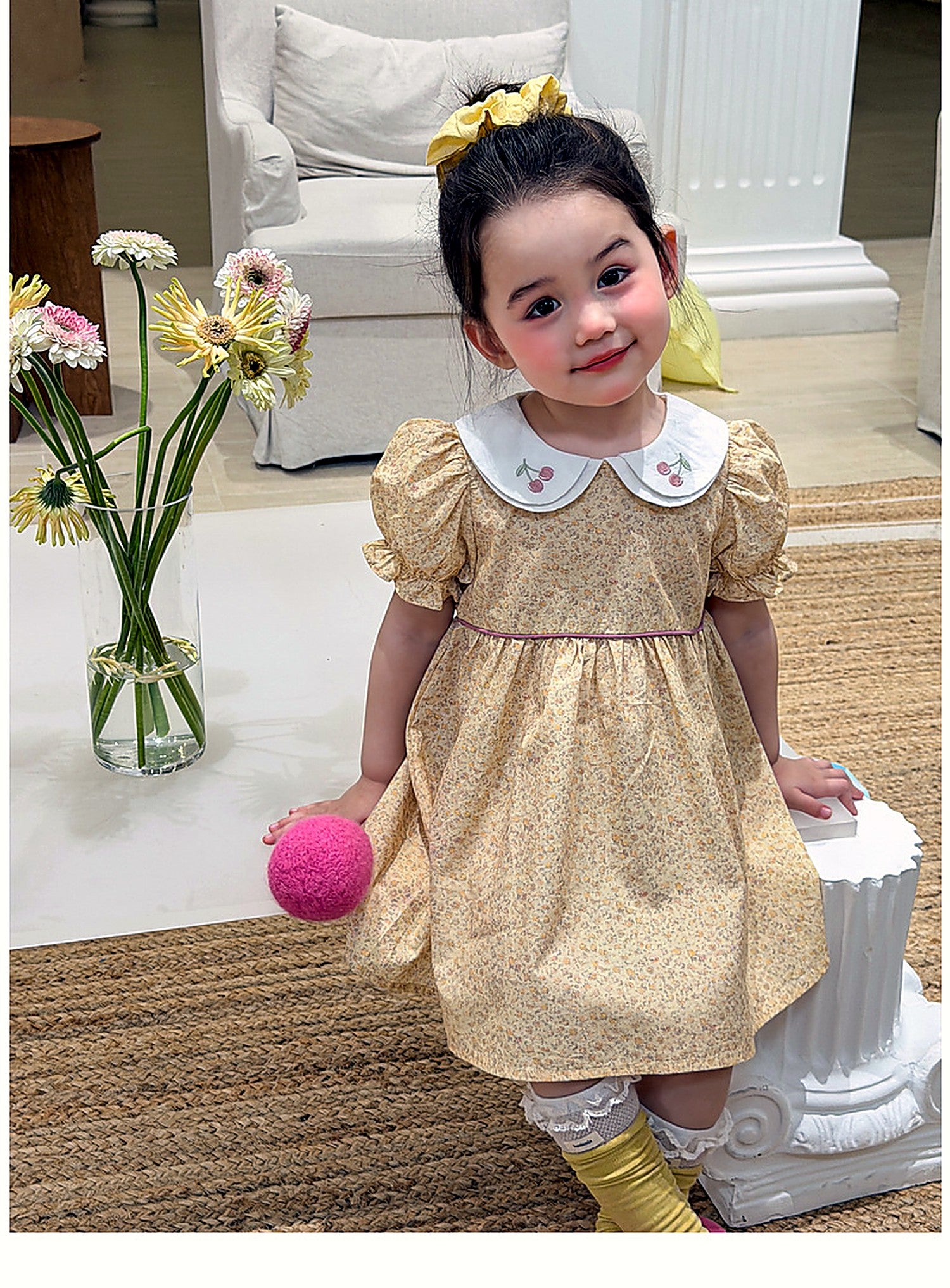 A young girl in the butter-yellow Cowslip Dress on a warm summer day.