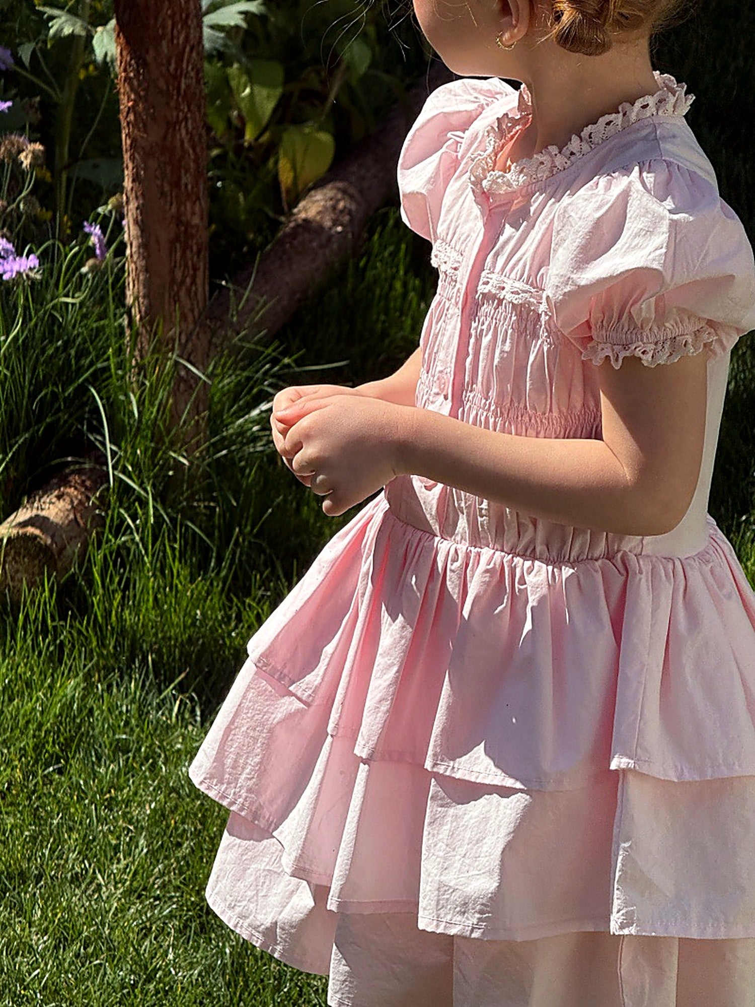 A girl in the Foxglove Dress among garden greenery, soft afternoon light.