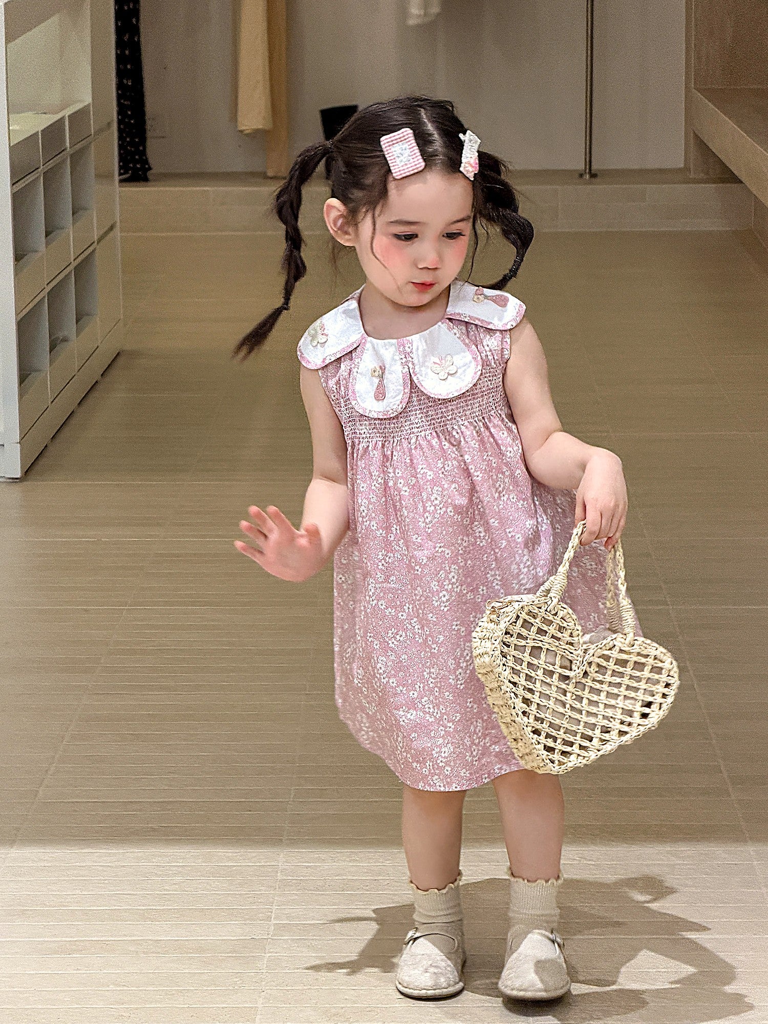 A young girl in a dusty-pink cotton dress with a white doll collar.