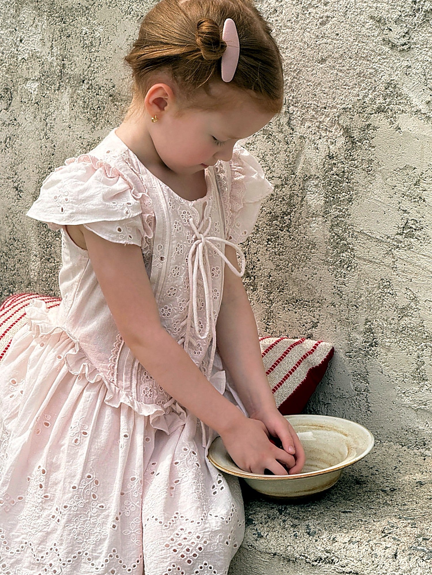The eyelet ruffled skirt of the Mallow Dress in faded pink.