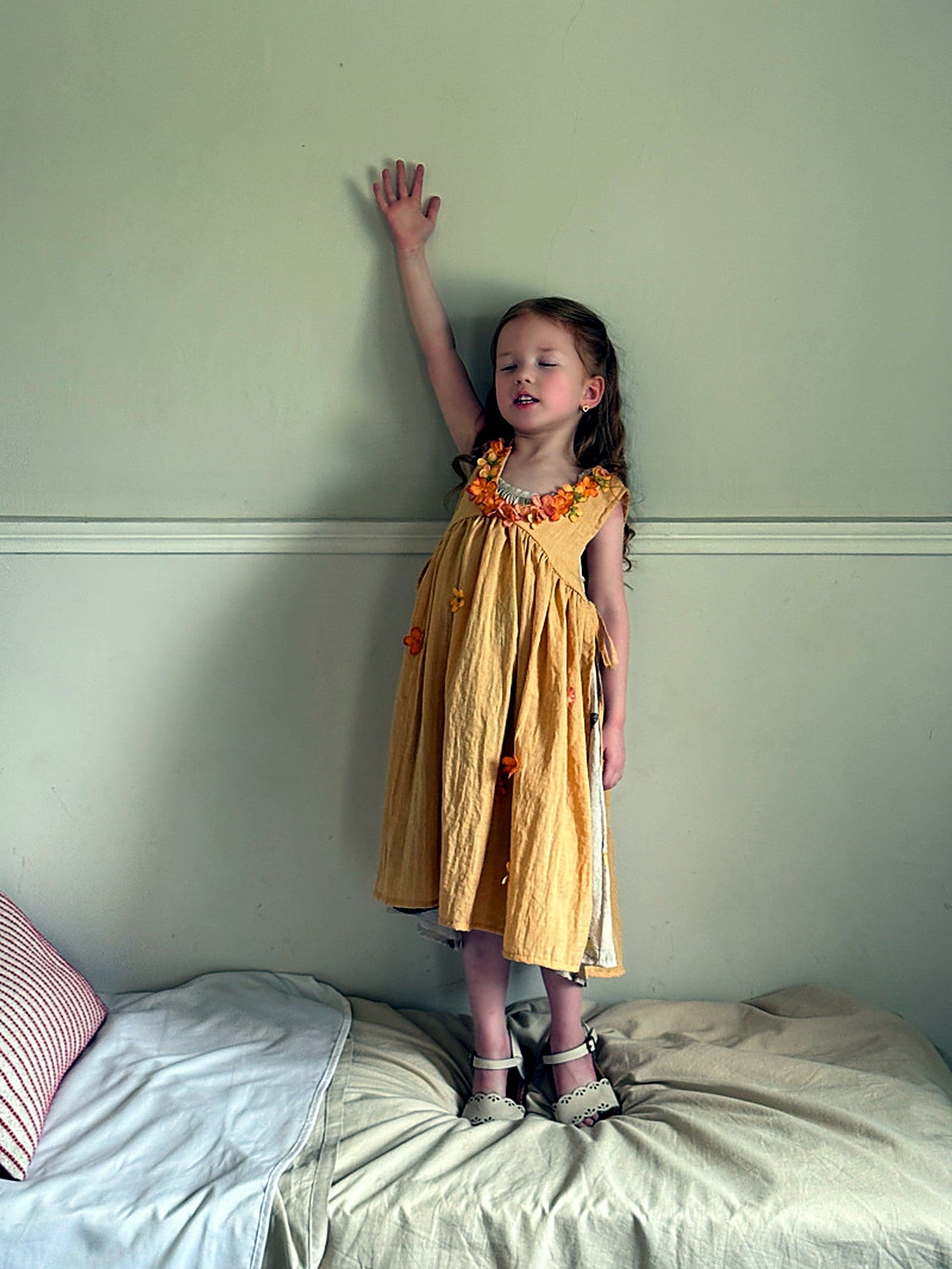 A girl in the warm mustard Marigold Dress on an unhurried summer afternoon indoors.