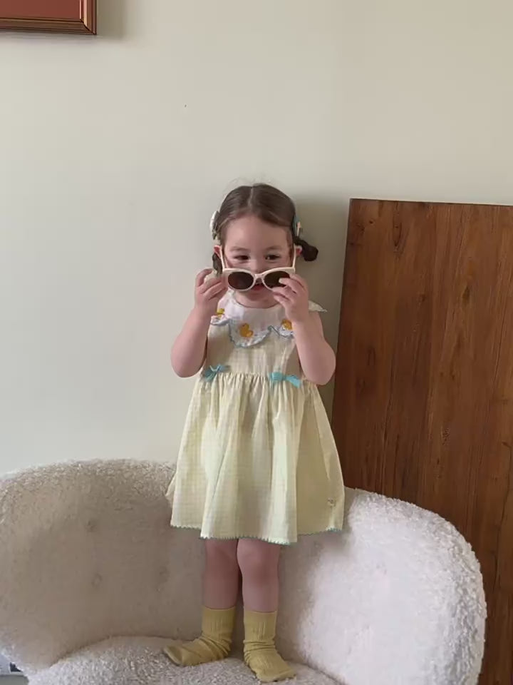 Short film of the Buttercup Pinafore — butter-yellow gingham with embroidered daisies and ducklings, in the light.