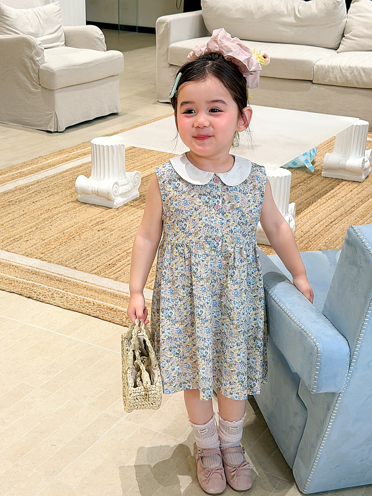 A toddler in the Speedwell Dress, a soft green summer dress.