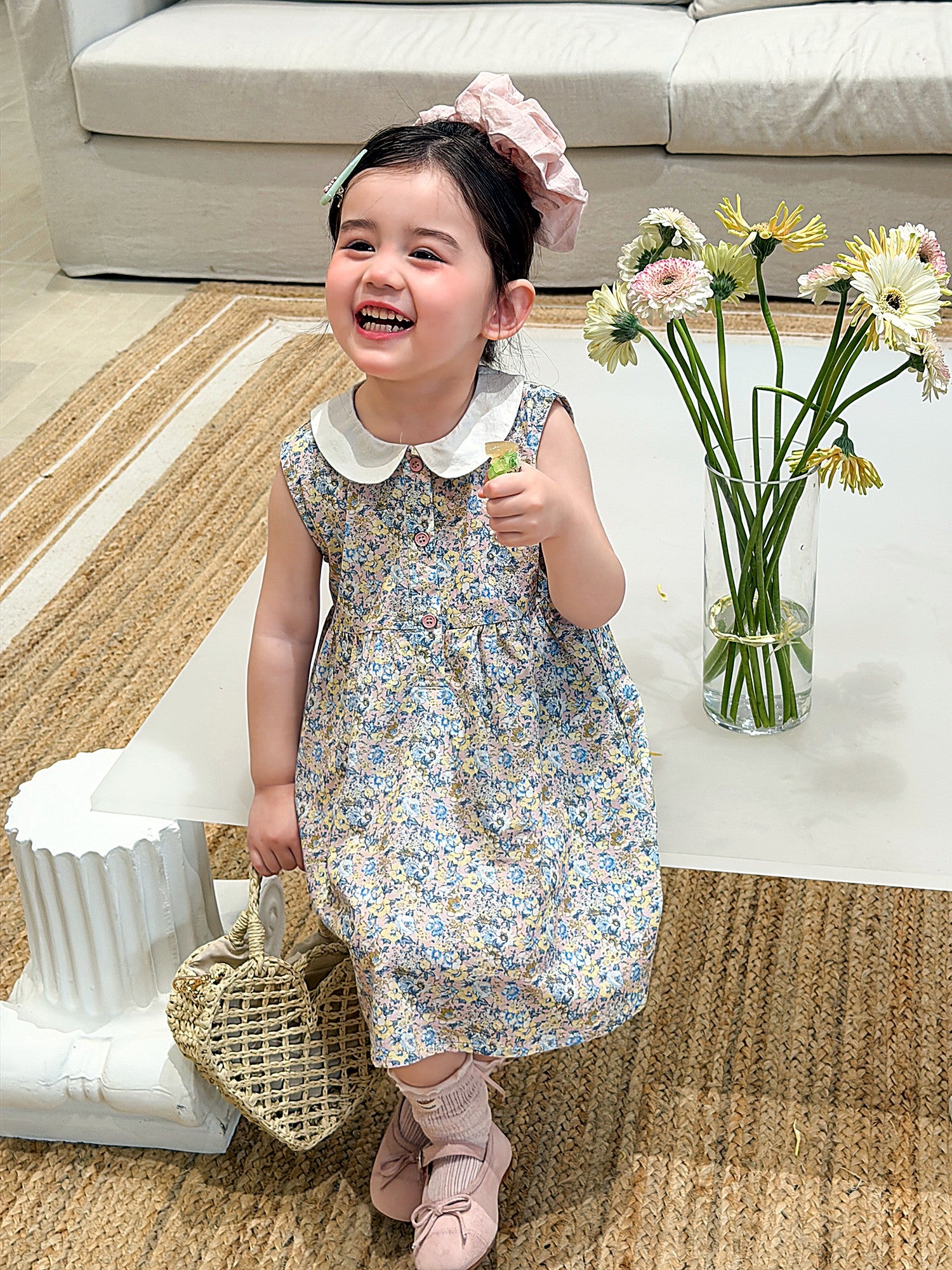 A young girl in a sage-green ditsy-floral cotton dress with a doll collar.