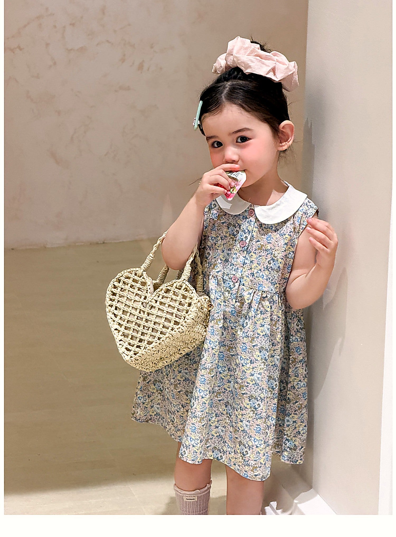 A toddler in the Speedwell Dress holding a basket, soft light.